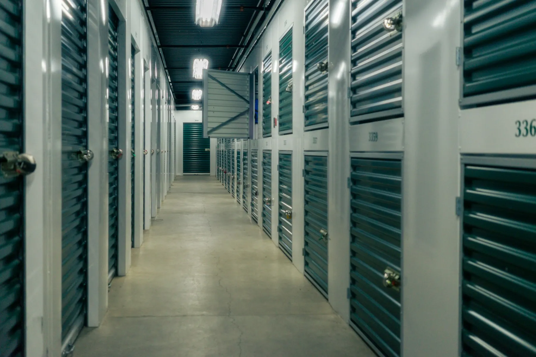 Indoor storage facility hallway with green roll-up unit doors